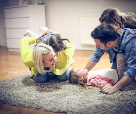 family playing on rug in electric heated house